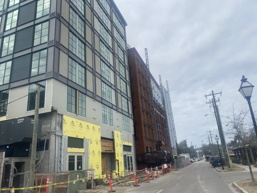 Street elevation mid-construction, finished upper floors above yellow weather barrier at grade