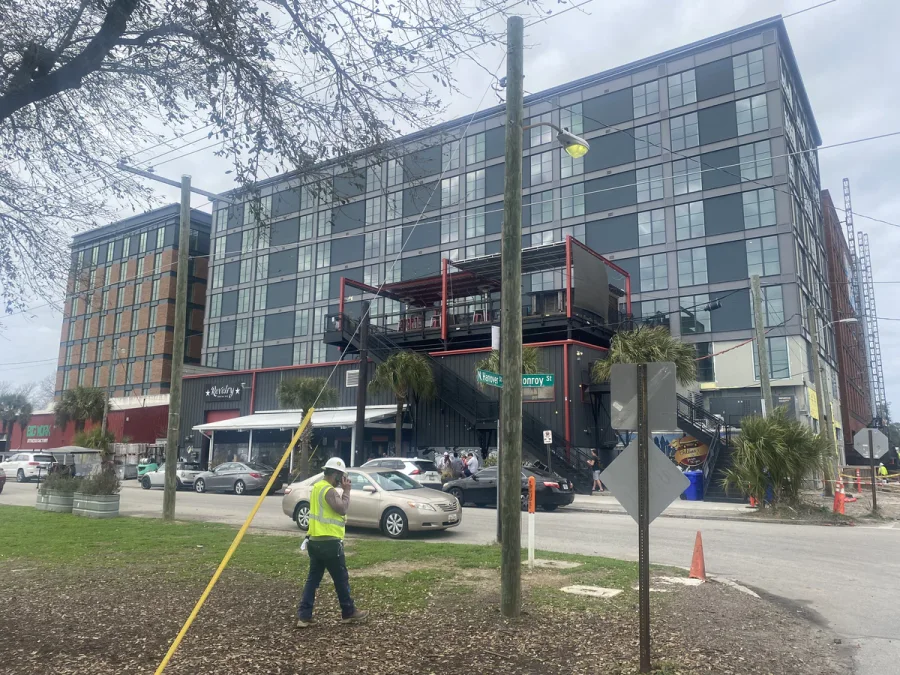 Crew member working the verge in front of a finished six-storey mixed-use facade