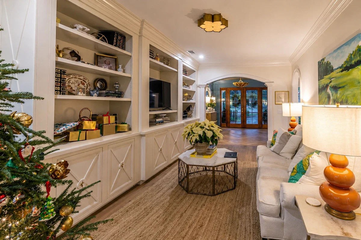 Living room with white painted built-in shelving and cabinetry finished beneath crown molding by J&I Coastal Painting
