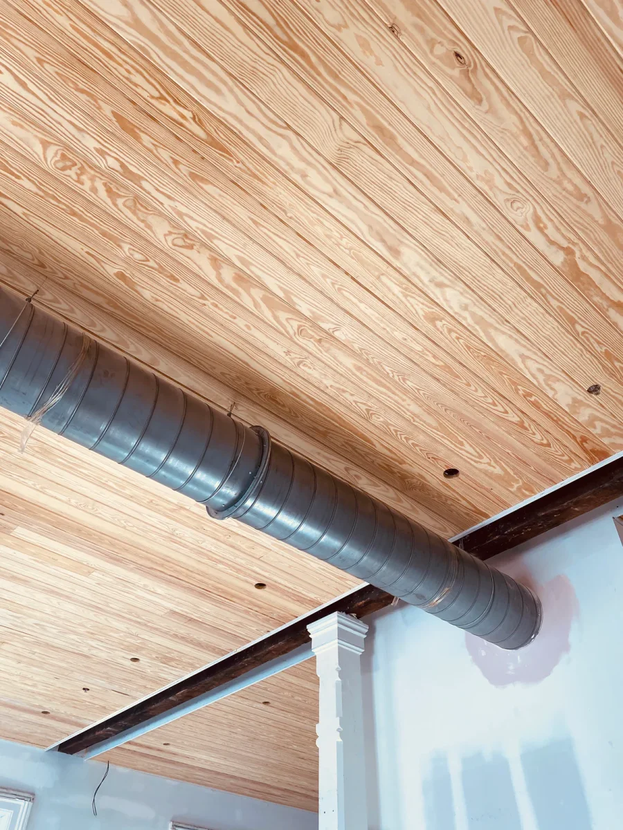 Pine plank ceiling fitted neatly around exposed spiral ductwork and a steel beam